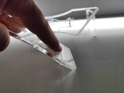 Aquakallax Algenschaber bei der Anwendung mit einem Finger auf dem transparenten Griff und der Schabkante auf einer glatten Fläche