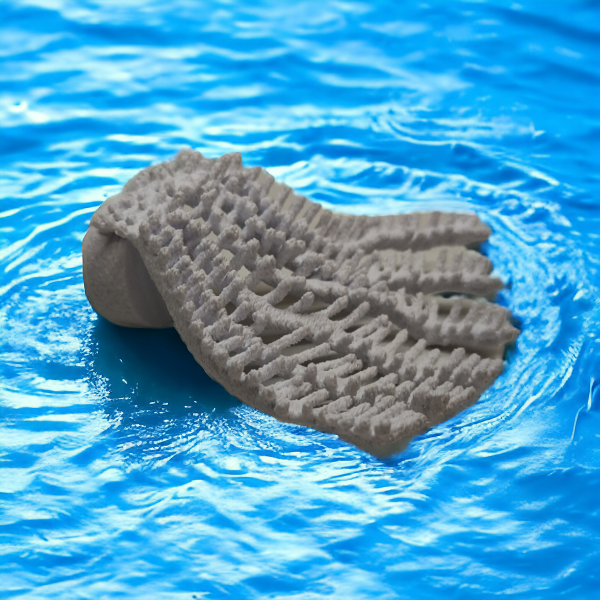 Weißer Aquakallax Magnetic Coral Fragträger in flacher Fächerform mit gerippter Korallenstruktur vor blauem Wasserhintergrund