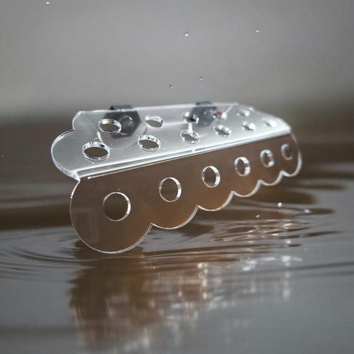 Transparenter Aquakallax ReefDeck für 17 Korallenplugs mit runden Öffnungen und Magnetbefestigung auf reflektierendem Wasserhintergrund