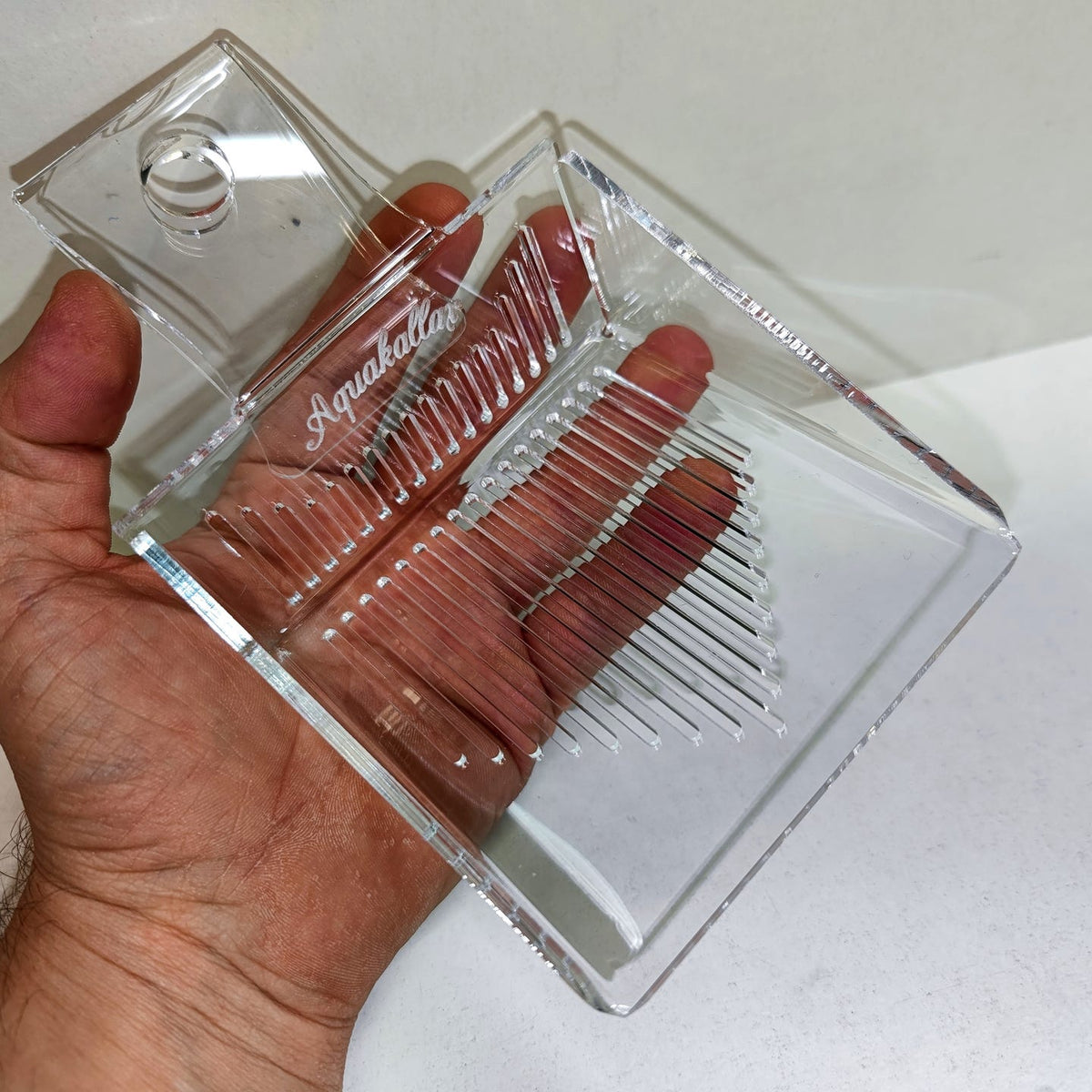 Transparente Aquakallax Schwimmpflanzenschaufel in einer Hand mit sichtbaren Ablauföffnungen